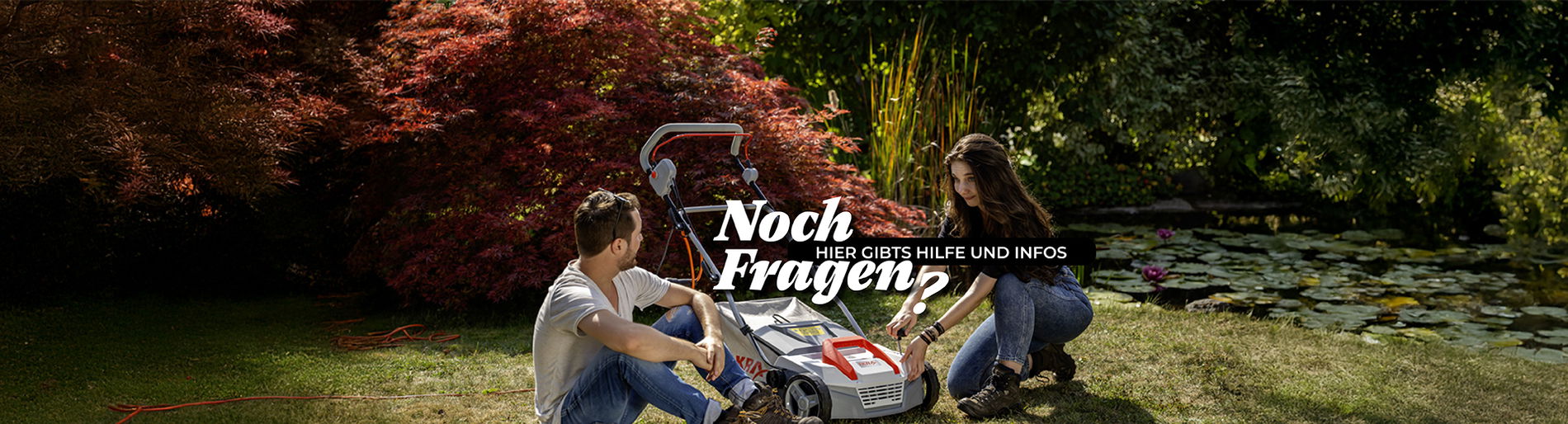 ein Mann und eine Frau knien vor einem Ikra Vertikutierer und erklären sich gegenseitig das Gerät.